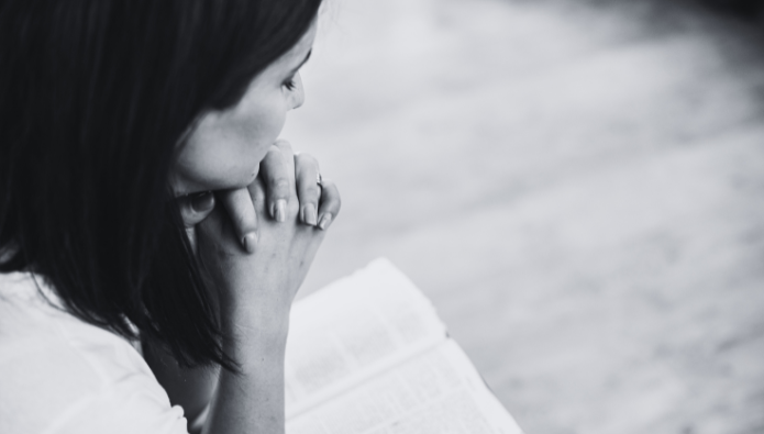 The Power of Prayer in Alleviating Anxiety - a woman praying with the bible in front of her