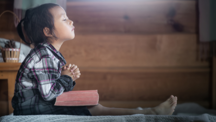 The Role of Prayer in Bible Reading - how to read the bible - a girl praying with the Bible on her lap